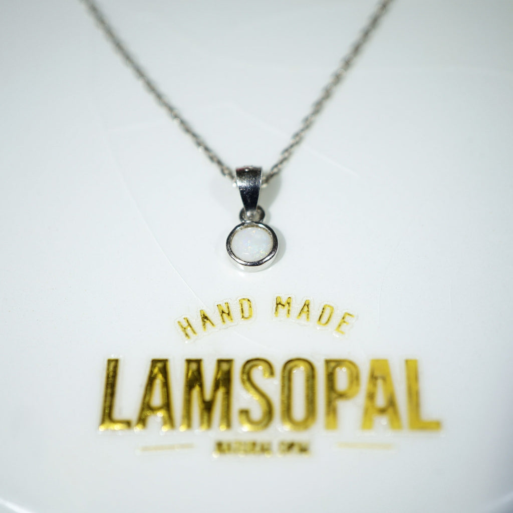 A silver chain necklace with a small circular pendant on a white display card. The card features gold foil text reading 'HAND MADE LAMSOPAL'.