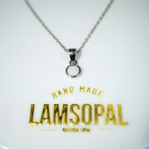 A silver chain necklace with a small circular pendant on a white display card. The card features gold foil text reading 'HAND MADE LAMSOPAL'.