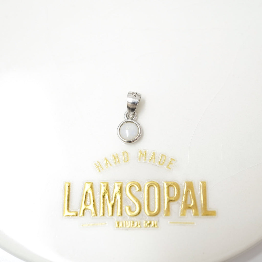 A silver pendant with a circular bezel-set white stone, displayed above gold foil branding that reads 'HAND MADE LAMSOPAL'.
