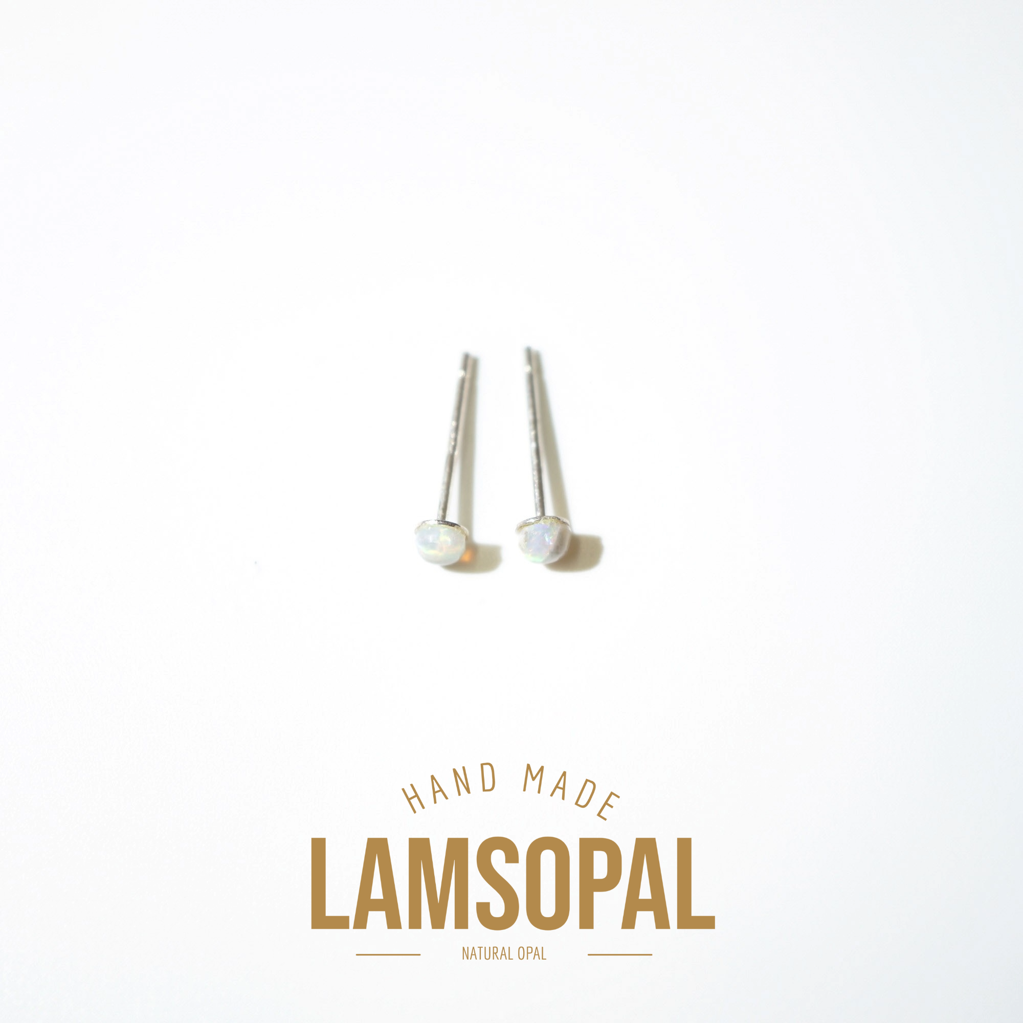 A pair of silver post earrings with round iridescent opal cabochons, displayed on a clean white background with a gold 'LAMSOPAL' brand logo and 'HAND MADE' text below.