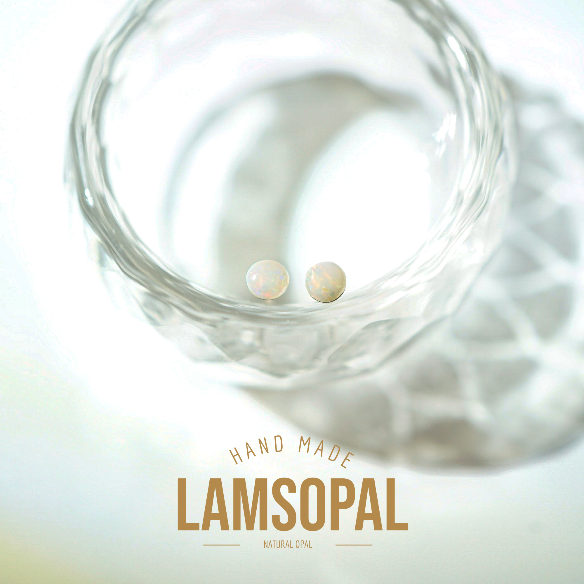 Two small round natural opal gemstones displayed inside a clear textured glass bowl, with the text 'HAND MADE LAMSOPAL NATURAL OPAL' at the bottom.