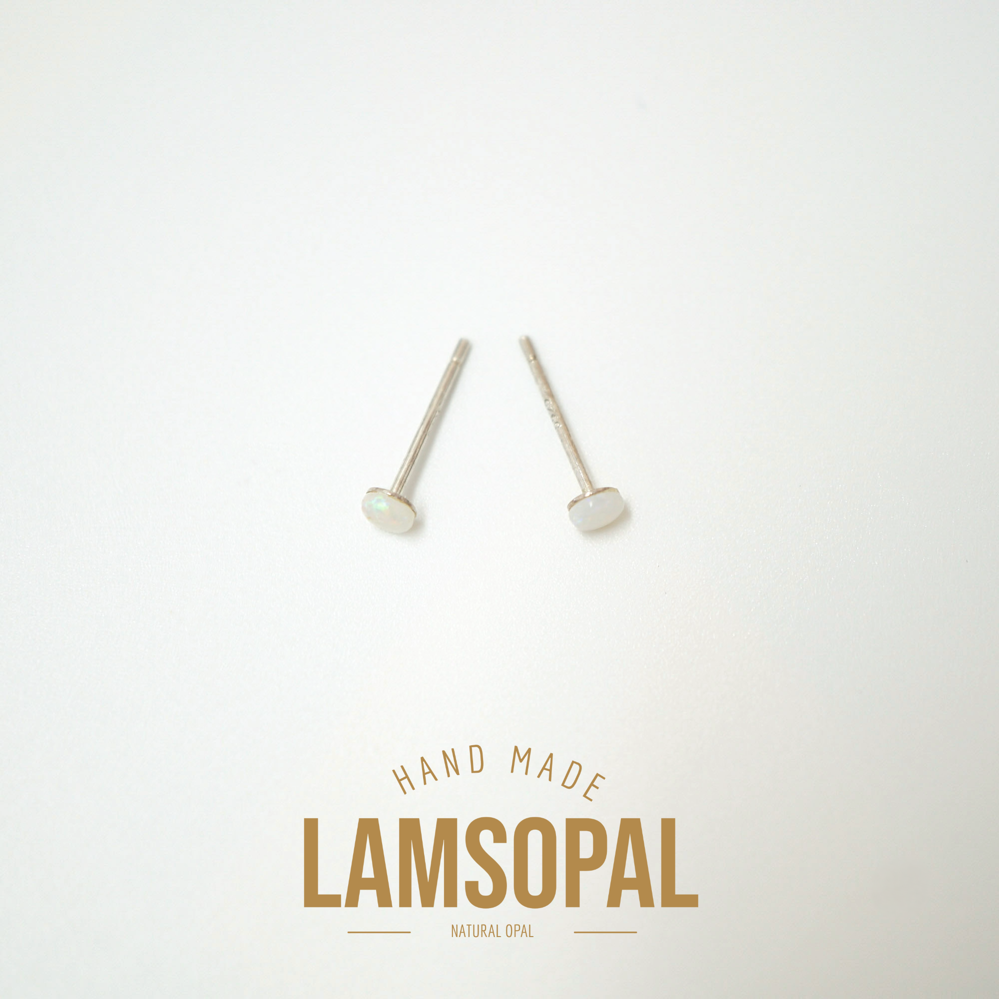 A pair of small natural opal stud earrings with silver posts, displayed on a clean white background with a gold 'LAMSOPAL HAND MADE' logo at the bottom.