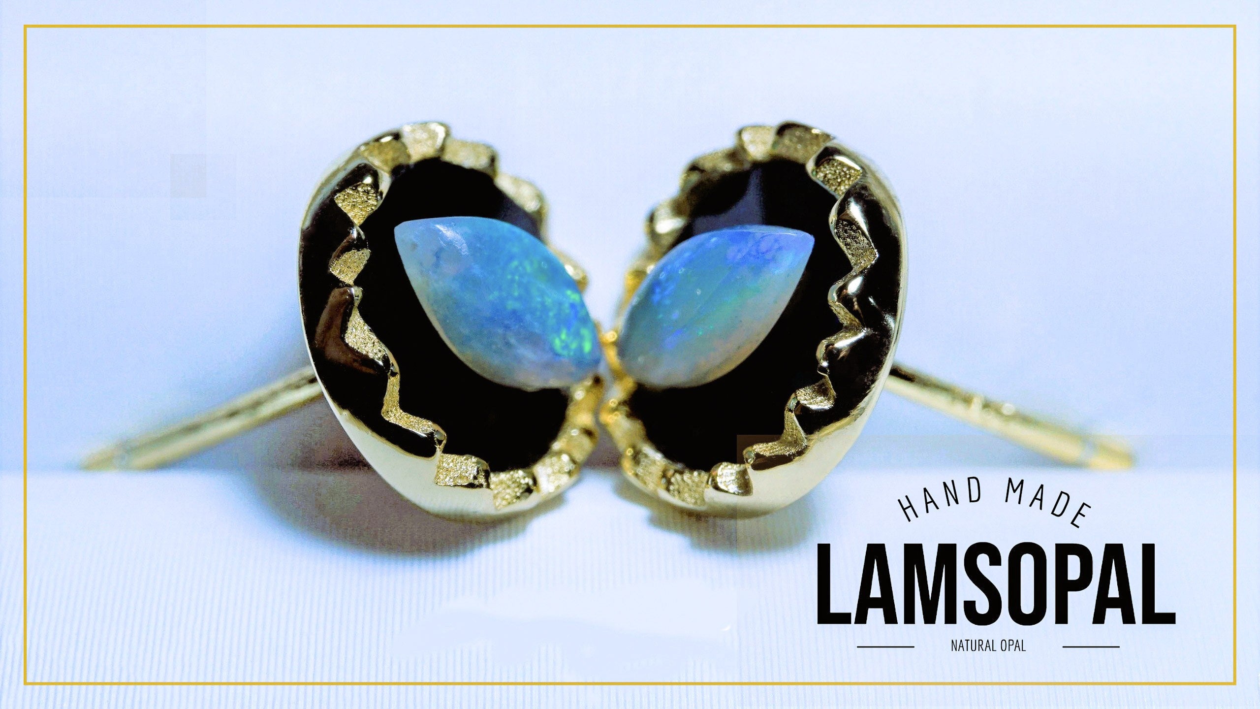 A pair of gold-toned stud earrings with teardrop-shaped natural opal stones, set in a black bezel with a textured gold border. The image features a 'HAND MADE LAMSOPAL' text overlay in the bottom right corner.