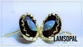 A pair of gold-toned lapel pins with oval black opal stones, featuring a wavy gold bezel setting and a post with a butterfly back. The image has a light blue background with a gold border, and a text overlay on the bottom right reads 'HAND MADE LAMSOPAL NATURAL OPAL'.