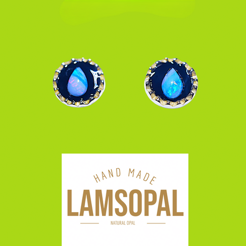 A pair of Lamsopal natural opal stud earrings with teardrop-shaped blue opal centers in silver bezel settings, displayed on a bright lime green background with a white label below reading 'HAND MADE LAMSOPAL NATURAL OPAL'.