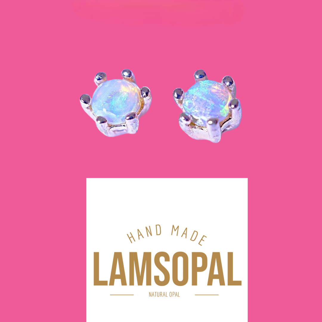 A pair of Lamsopal natural opal stud earrings set in silver, displayed on a vibrant pink background with a white brand card below.