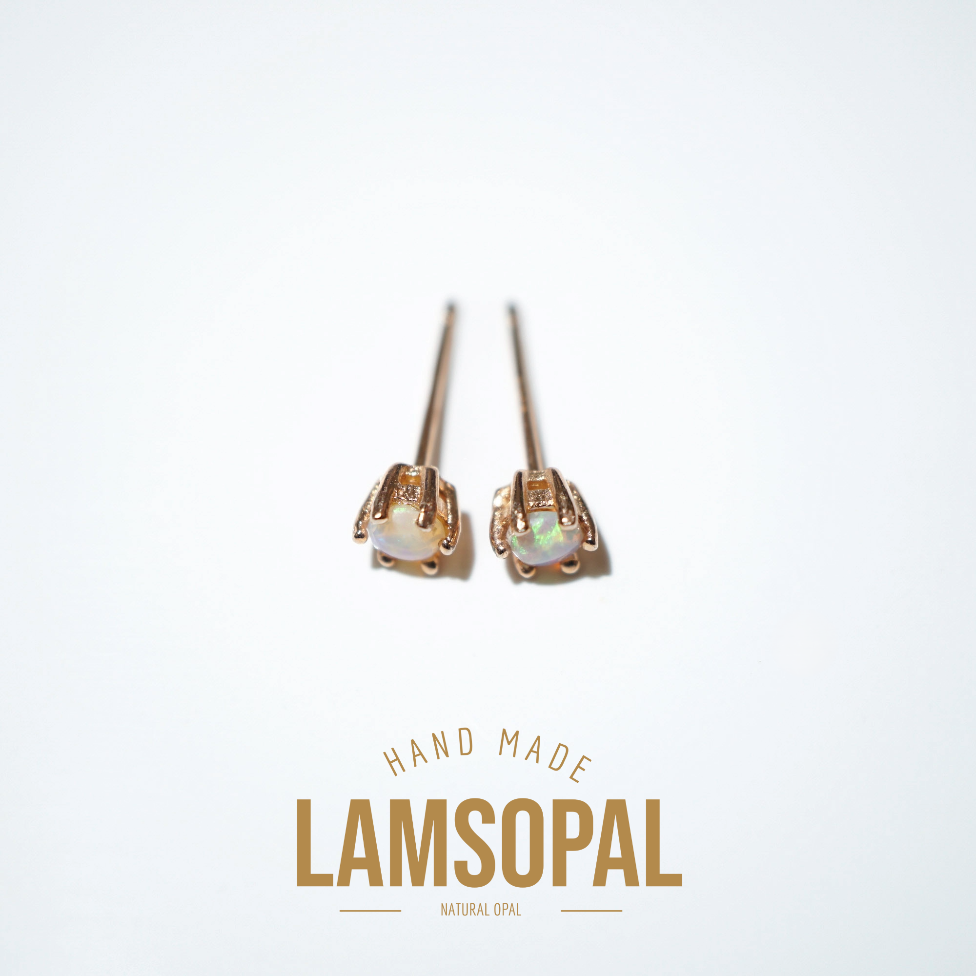 A pair of rose gold stud earrings with natural opal gemstones, displayed on a clean white background with the brand name 'LAMSOPAL' and 'HAND MADE' text below.