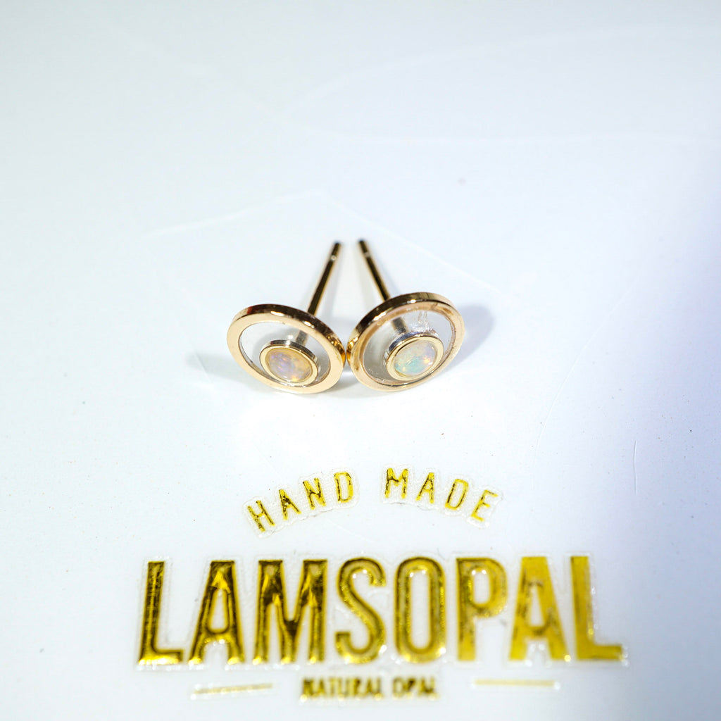 A pair of gold-toned oval stud earrings with natural opal inlays, displayed on a white surface above a gold 'LAMSOPAL' brand logo.
