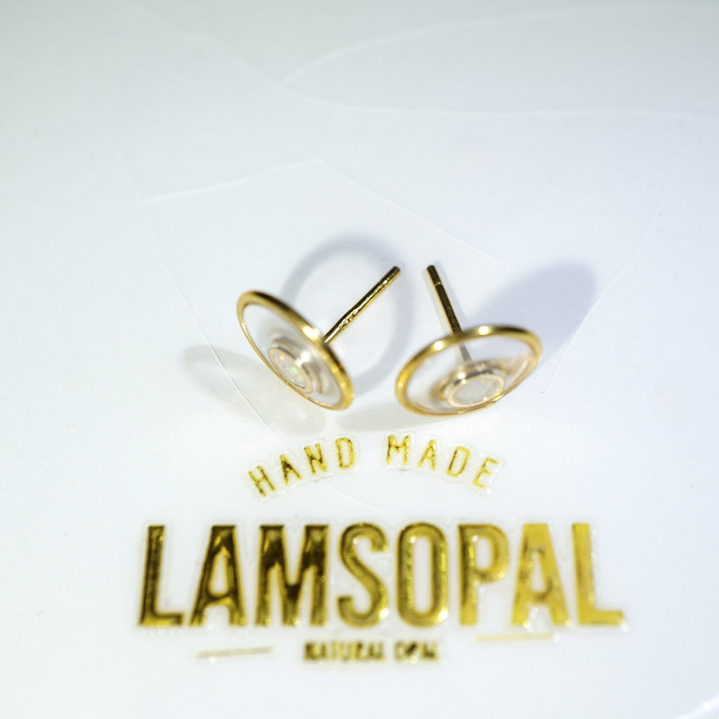 A pair of gold-toned flat-back stud earrings displayed on a white card with the brand name 'LAMSOPAL' and 'HAND MADE' printed below.