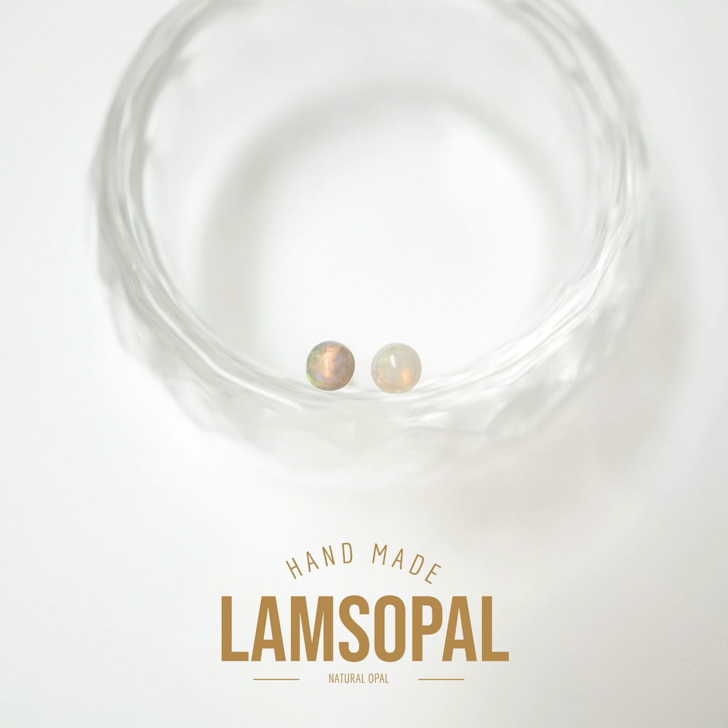 Two small round natural opal gemstones displayed inside a clear textured glass bowl, with the text 'HAND MADE LAMSOPAL NATURAL OPAL' below on a white background.