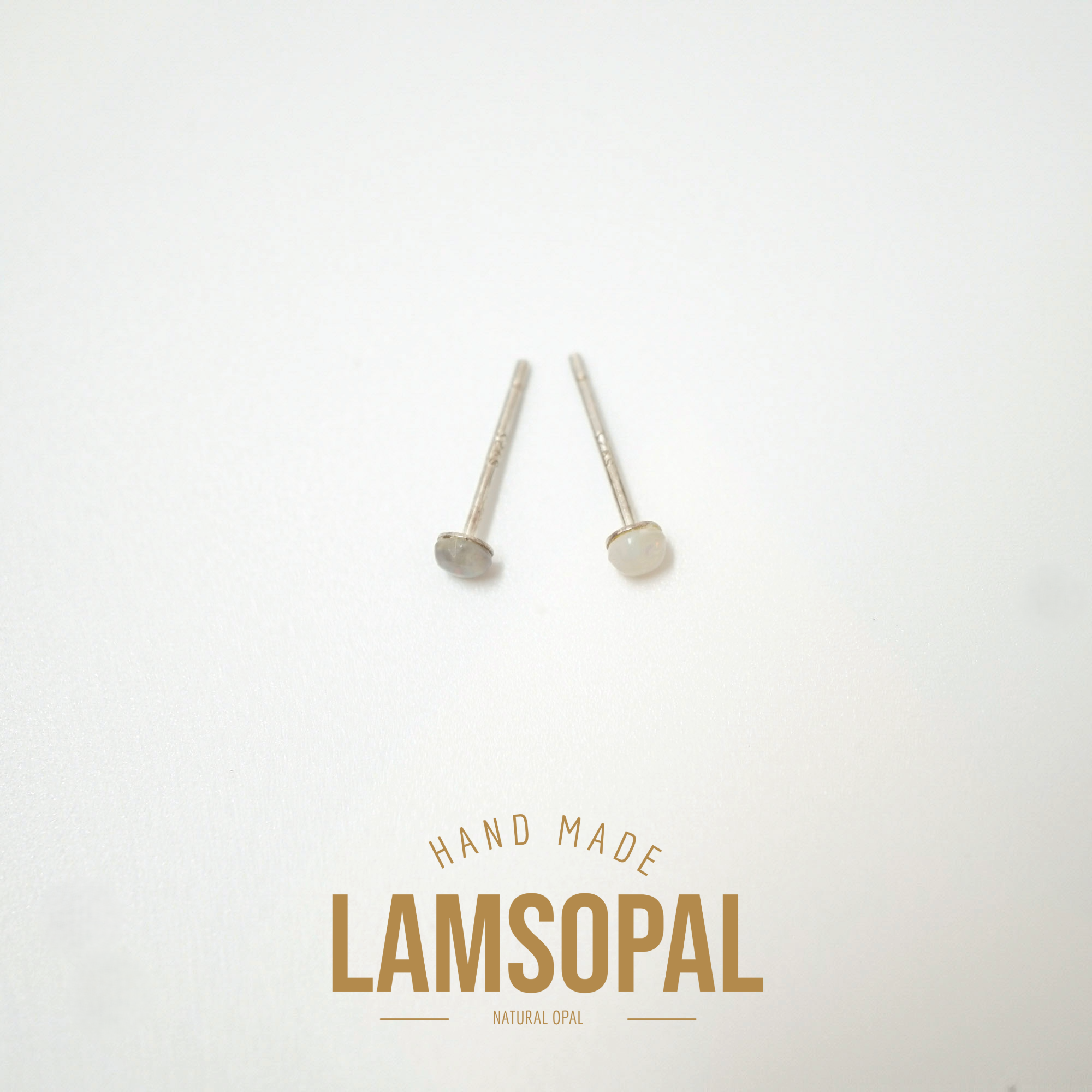Two small silver stud earrings with oval clear stones on a white background, with the text 'HAND MADE LAMSOPAL NATURAL OPAL' printed below.