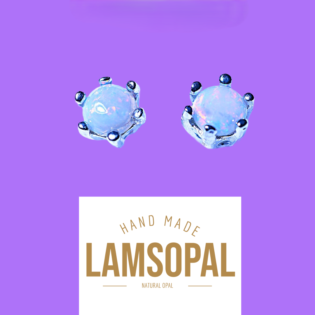 Two small round light blue opal gemstone stud earrings with silver prongs, displayed on a purple background above a white label that reads 'HAND MADE LAMSOPAL NATURAL OPAL'.
