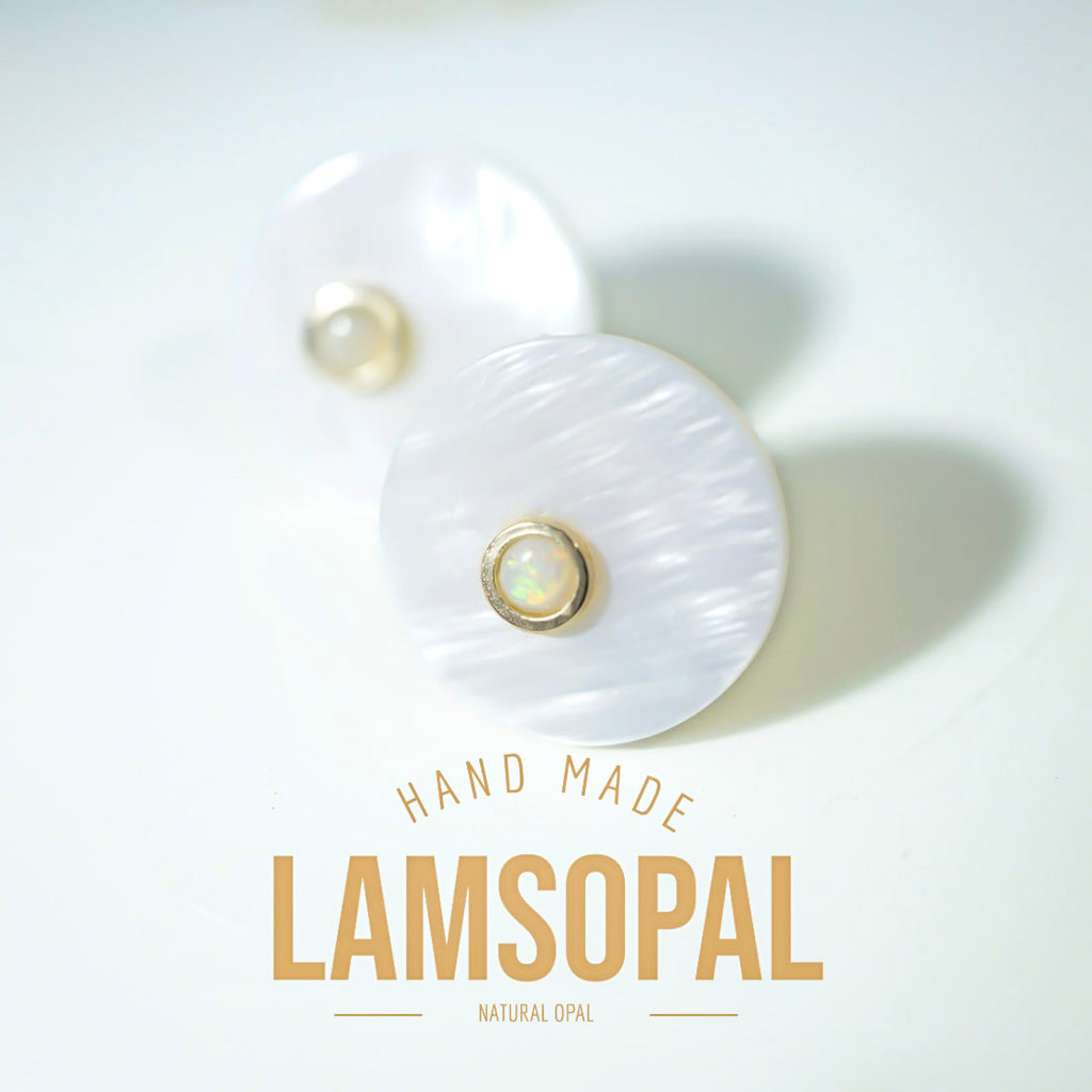 A pair of handmade Lamsopal natural opal stud earrings with round white mother-of-pearl discs and gold bezel-set iridescent opal centers, displayed on a clean white background with 'HAND MADE LAMSOPAL' text below.