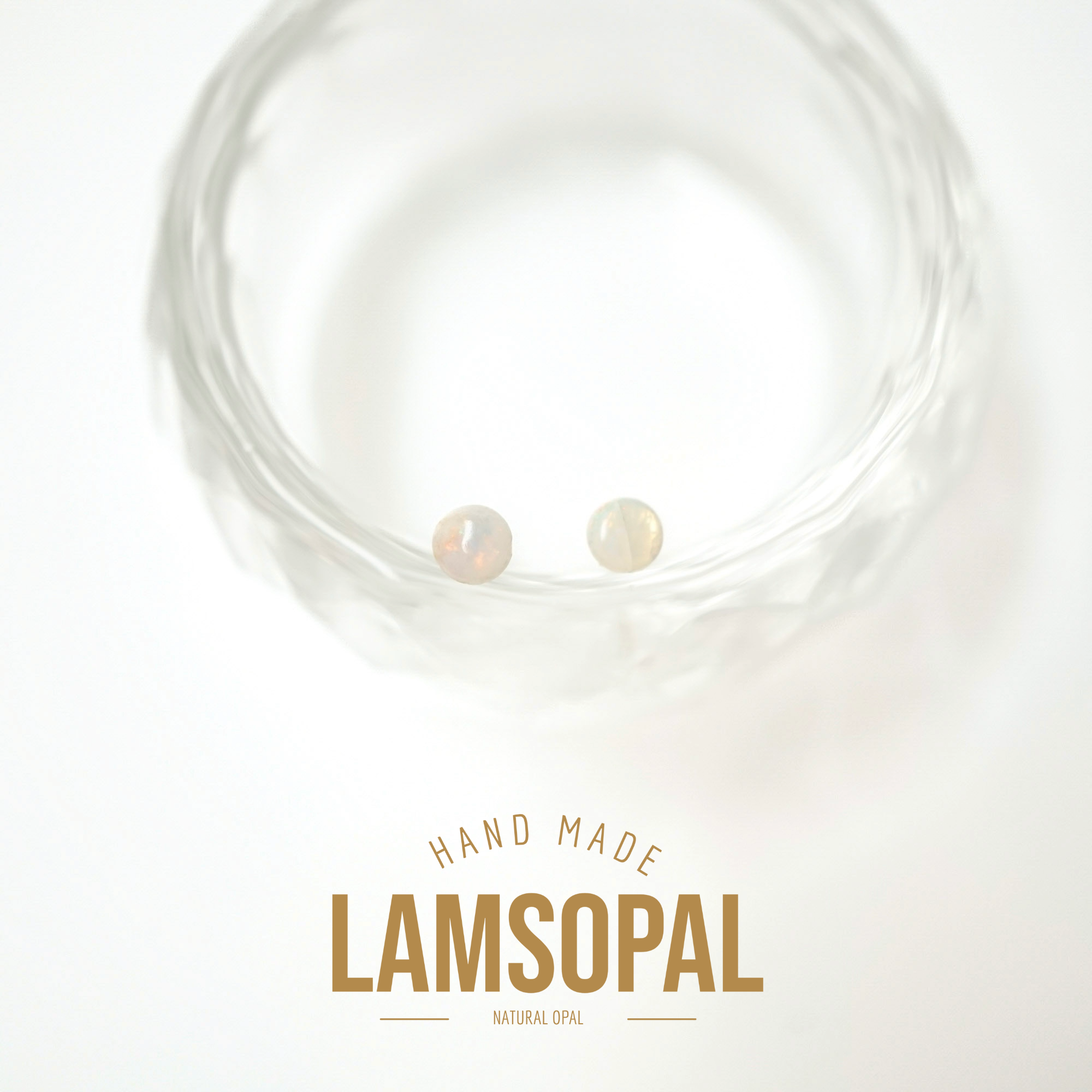 Two small natural opal gemstones displayed inside a clear textured glass bowl, with text below reading 'HAND MADE LAMSOPAL NATURAL OPAL' on a white background.