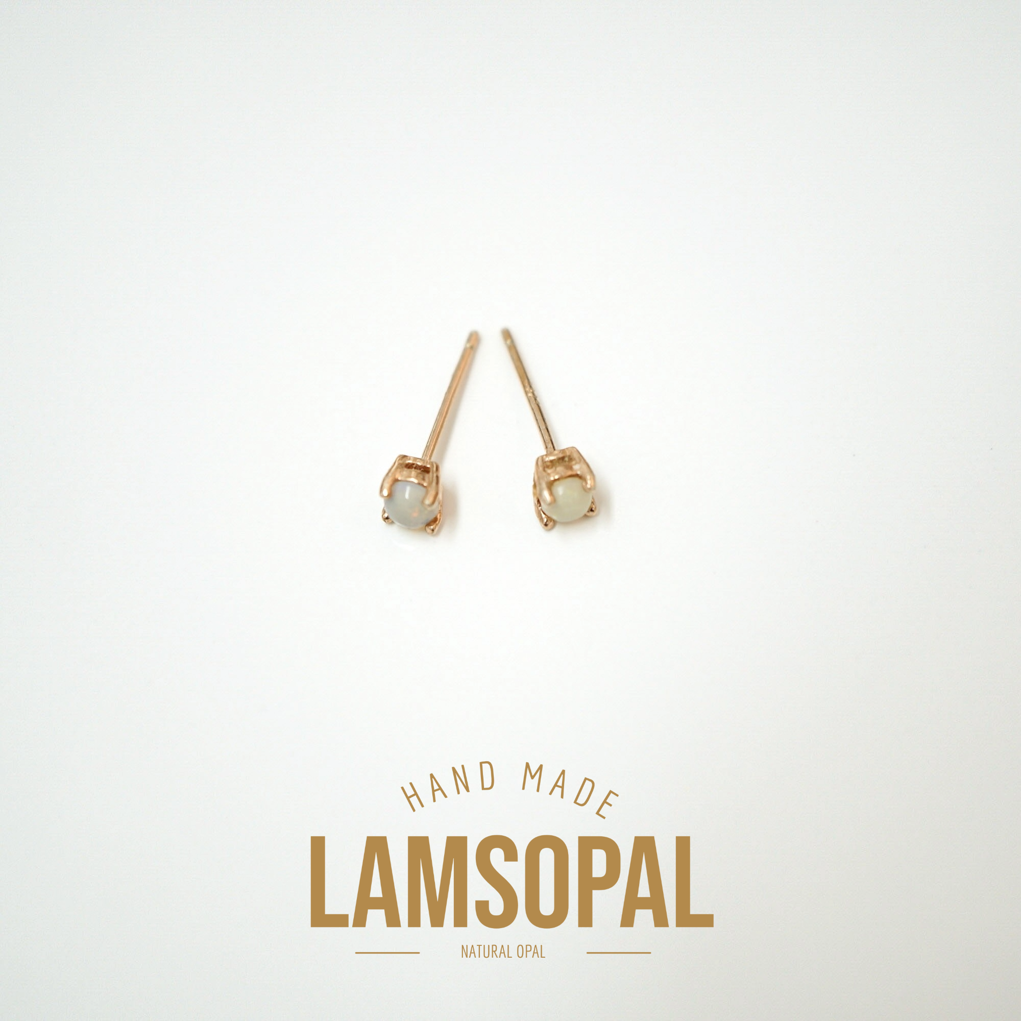 A pair of small gold stud earrings with oval pale green stones, shown on a clean white background above the text 'HAND MADE LAMSOPAL NATURAL OPAL'.