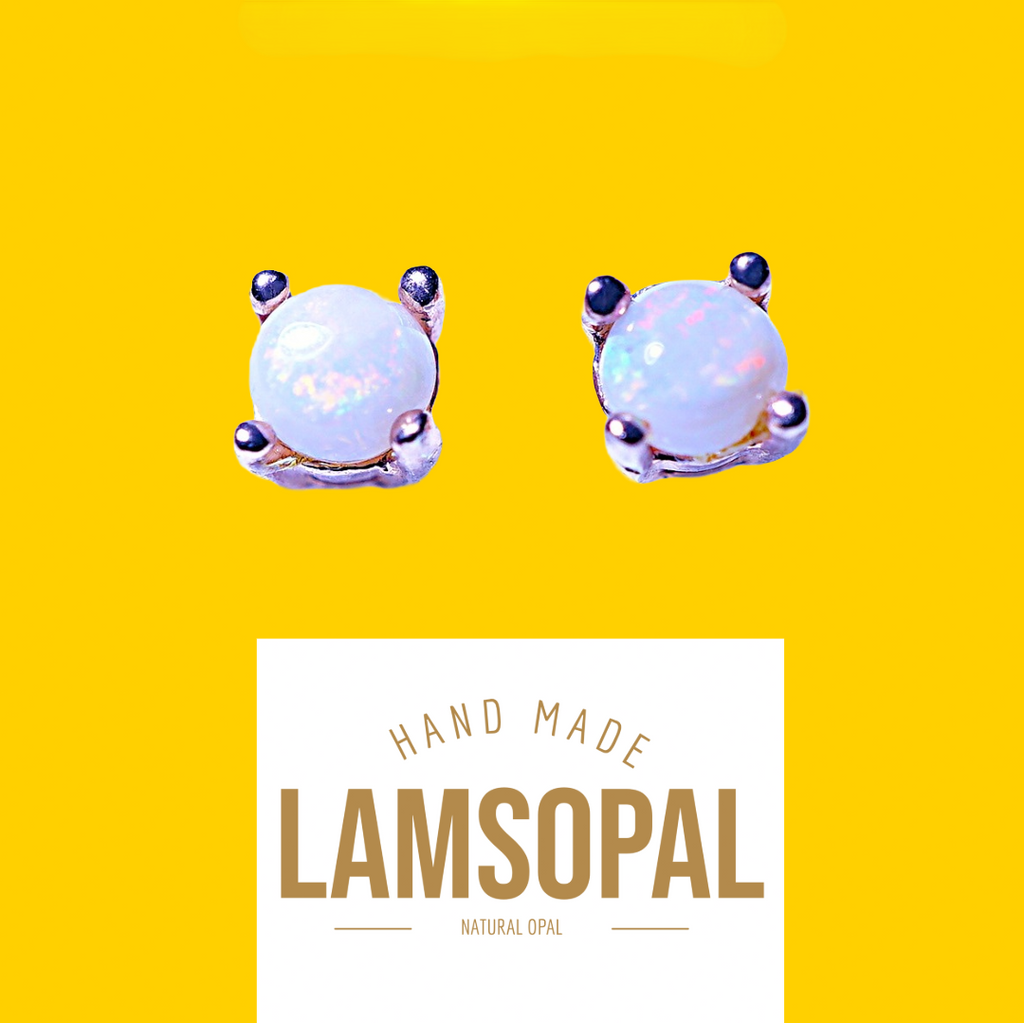 A pair of Lamsopal hand-made natural opal stud earrings in a silver-toned setting, displayed on a bright yellow background with a white label below.