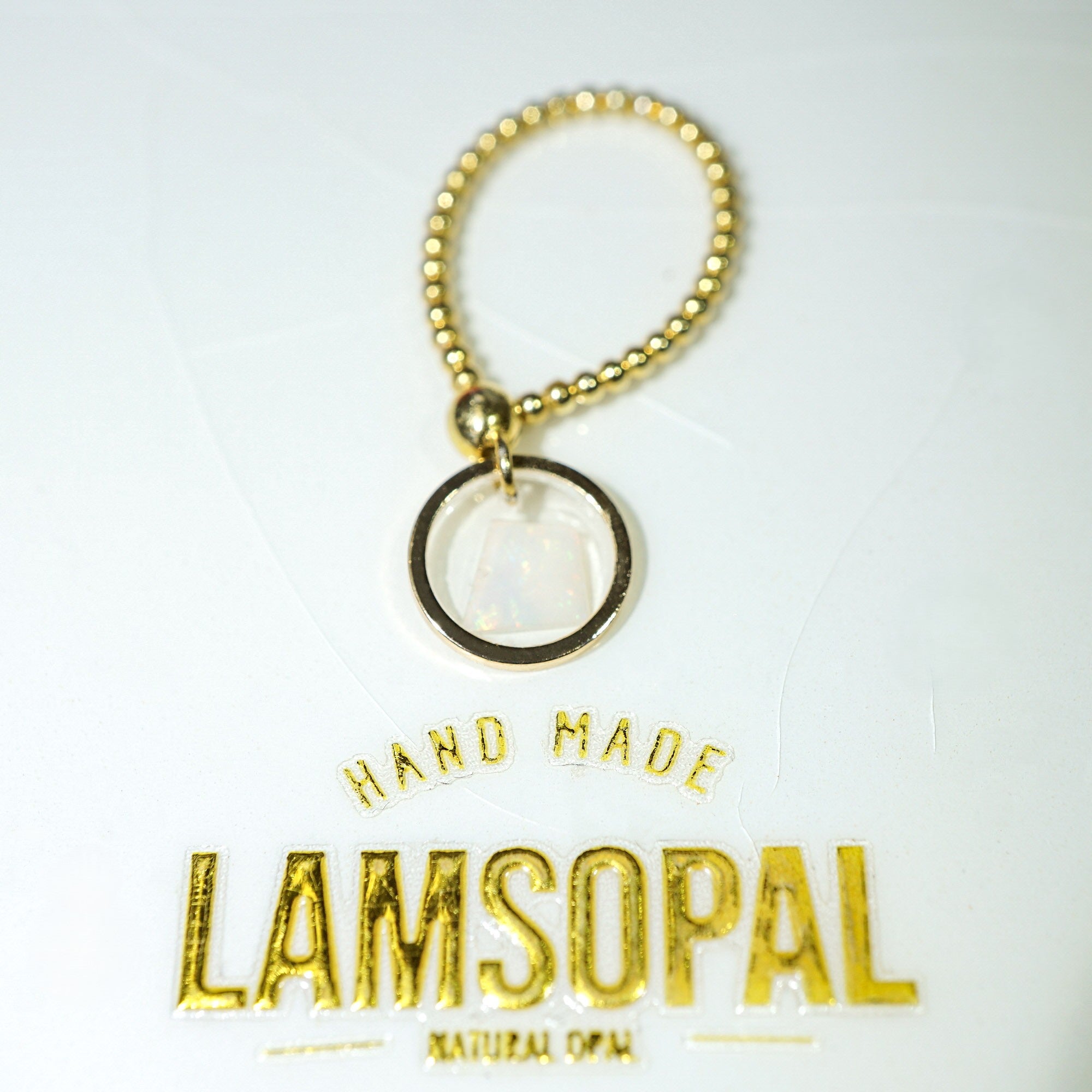 A gold-tone beaded keychain or bag charm with a circular pendant, shown on a white background with the brand name 'Lamsopal' printed below.