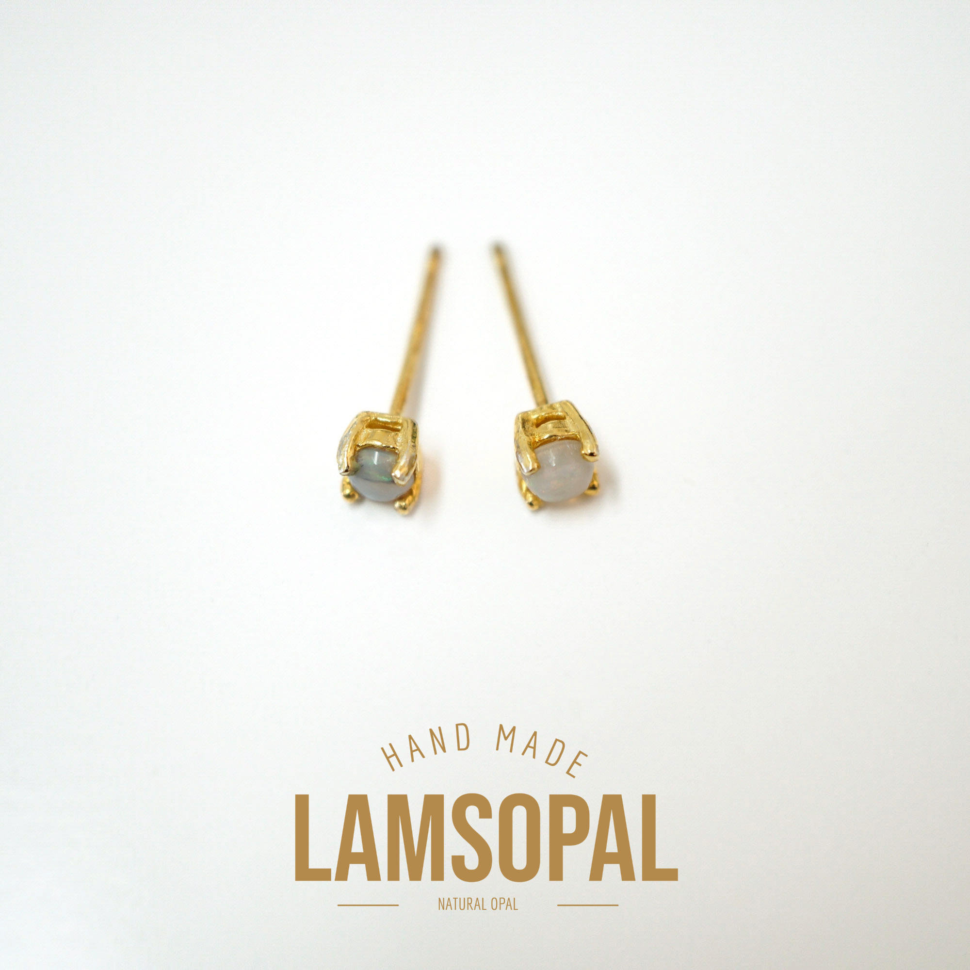 A pair of gold stud earrings with natural opal gemstones, displayed on a clean white background with a gold 'LAMSOPAL' brand logo and 'HAND MADE' text below.
