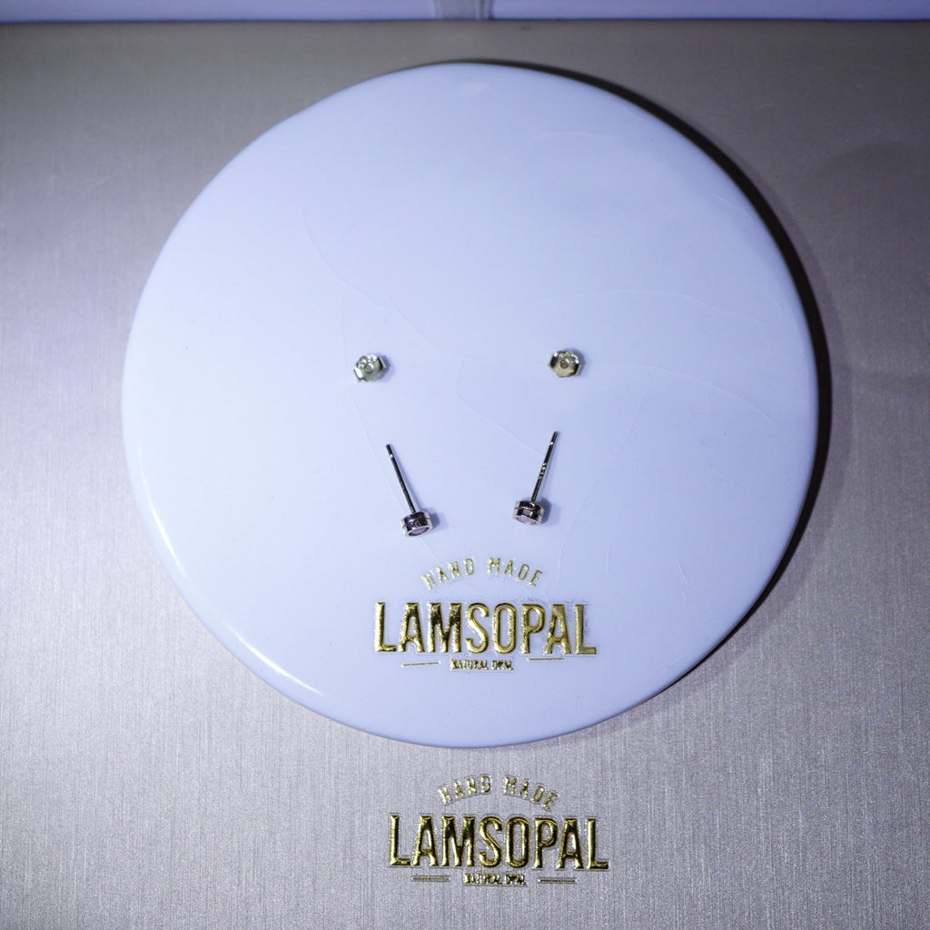 A pair of small gold-toned stud earrings displayed on a round white branded backing card. The card shows the brand name Lamsopal in gold lettering and reads 'Hand Made Lamsopal London.