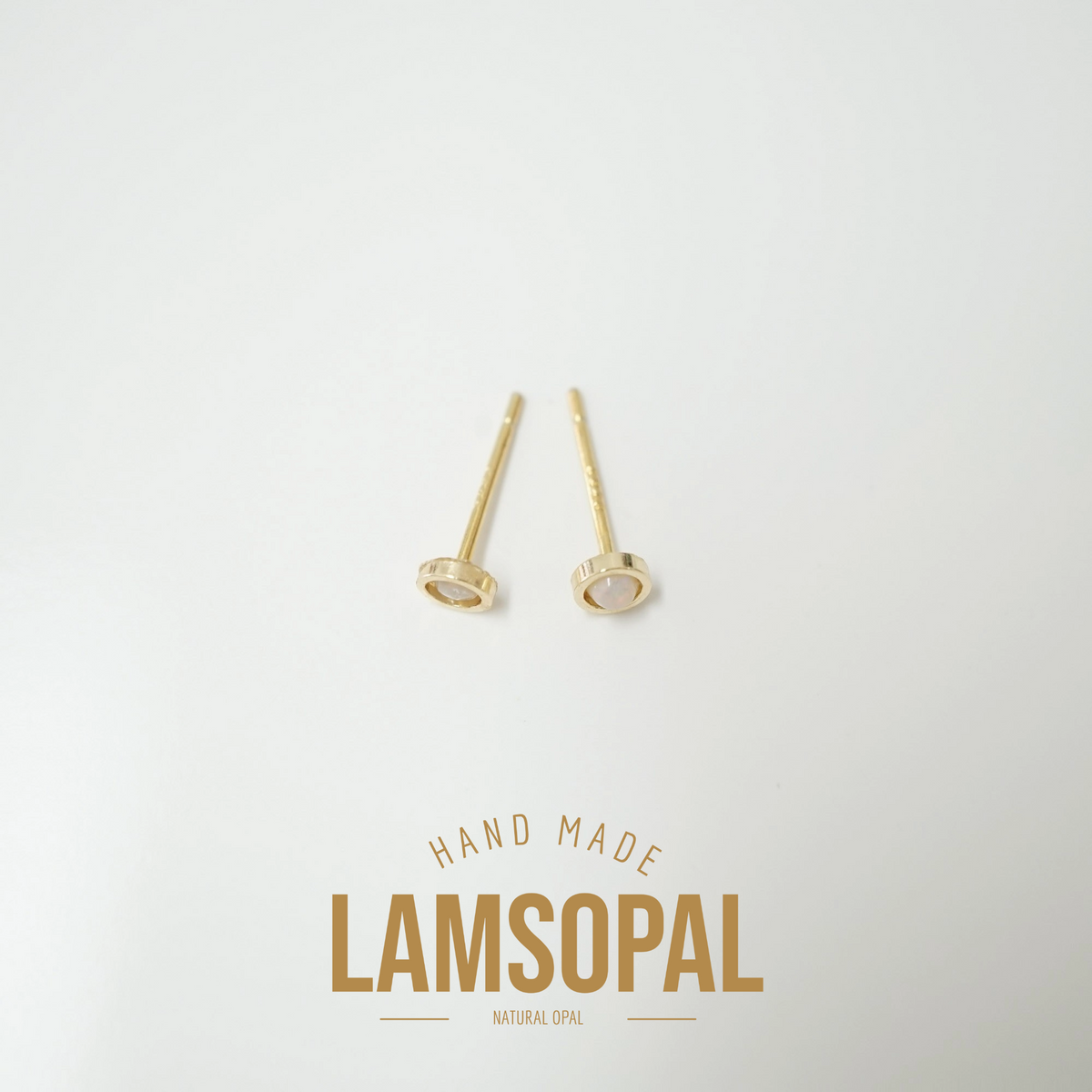 A pair of gold post earrings with oval settings on a light gray background, with the text 'HAND MADE LAMSOPAL' printed below.