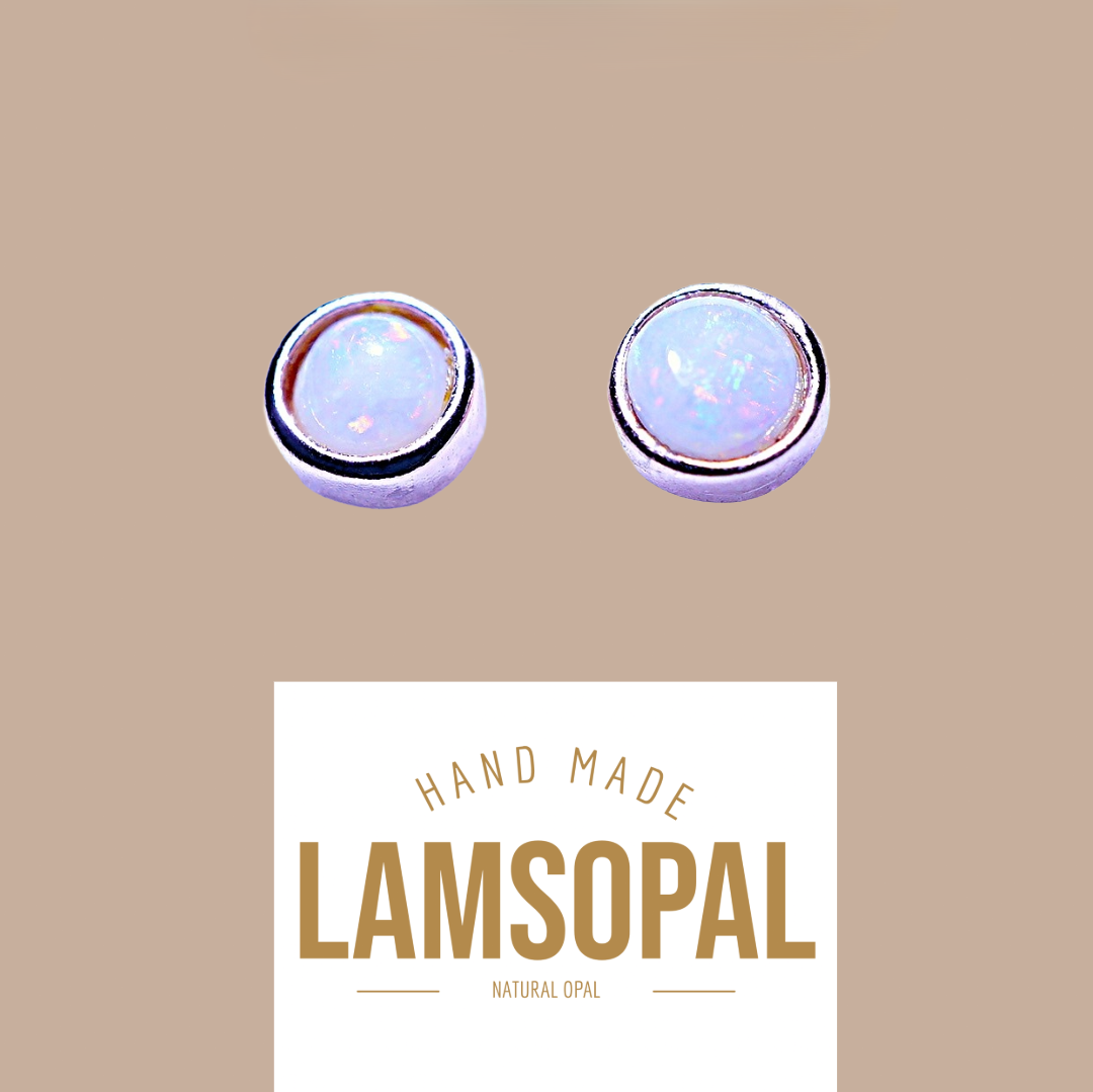 Two round natural opal stud earrings with silver bezels, shown above a white label that reads 'HAND MADE LAMSOPAL NATURAL OPAL' on a solid tan background.