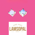 A pair of handmade Lamsopal natural opal stud earrings with gold settings, displayed on a vibrant pink background with a white label below that reads 'HAND MADE LAMSOPAL NATURAL OPAL'.