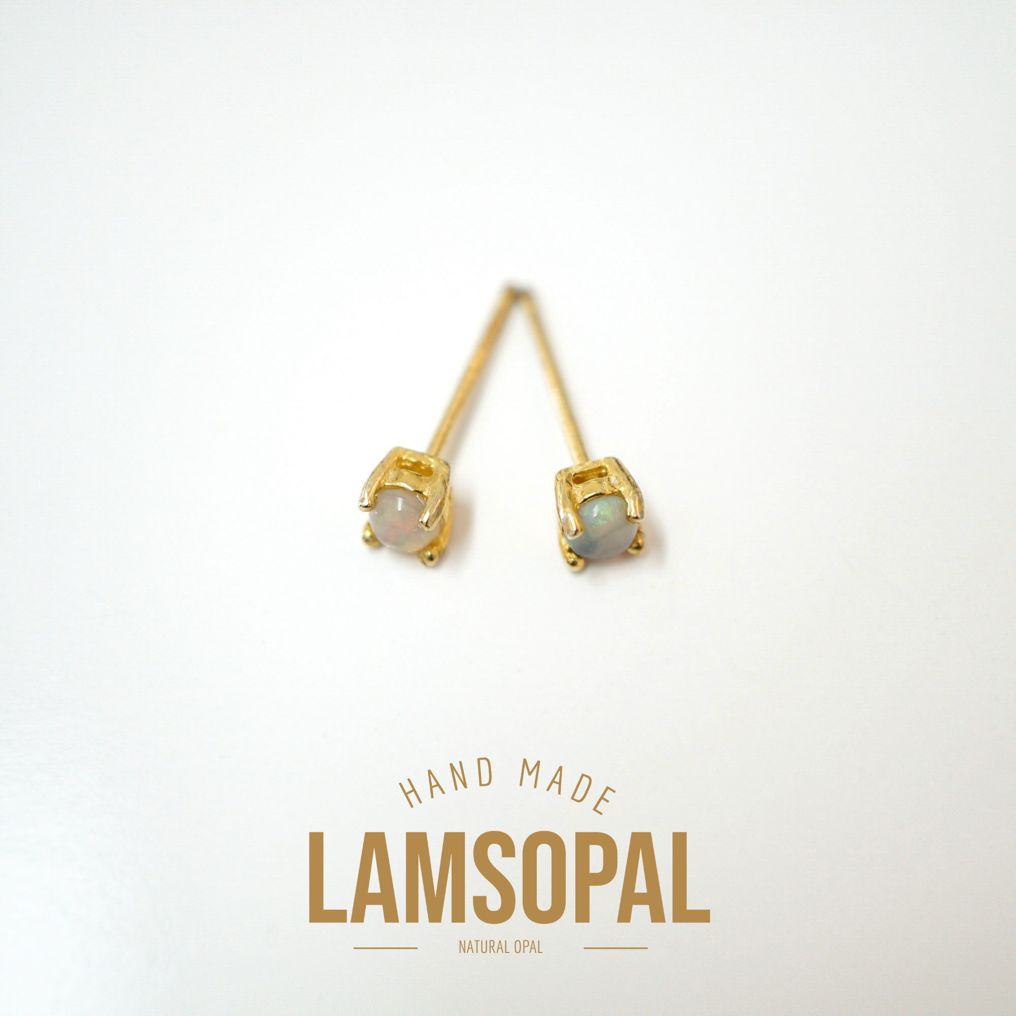 A pair of gold stud earrings with natural opal gemstones, displayed on a clean white background with a gold 'LAMSOPAL' brand logo and 'HAND MADE' text below.