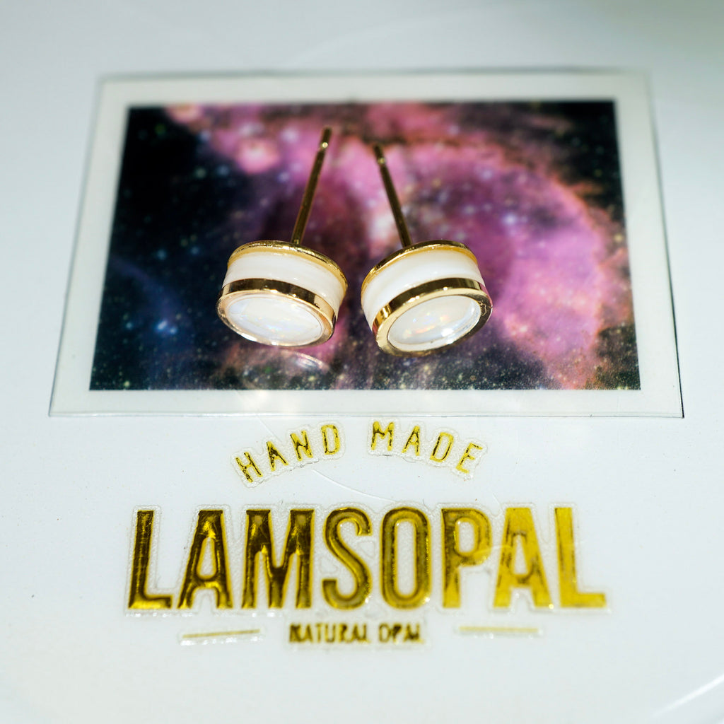 A pair of handmade stud earrings with white circular tops and gold borders, displayed on a branded card that reads 'HAND MADE LAMSOPAL NATURAL OPAL'.