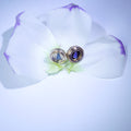 Pair of earrings on a white orchid flower
