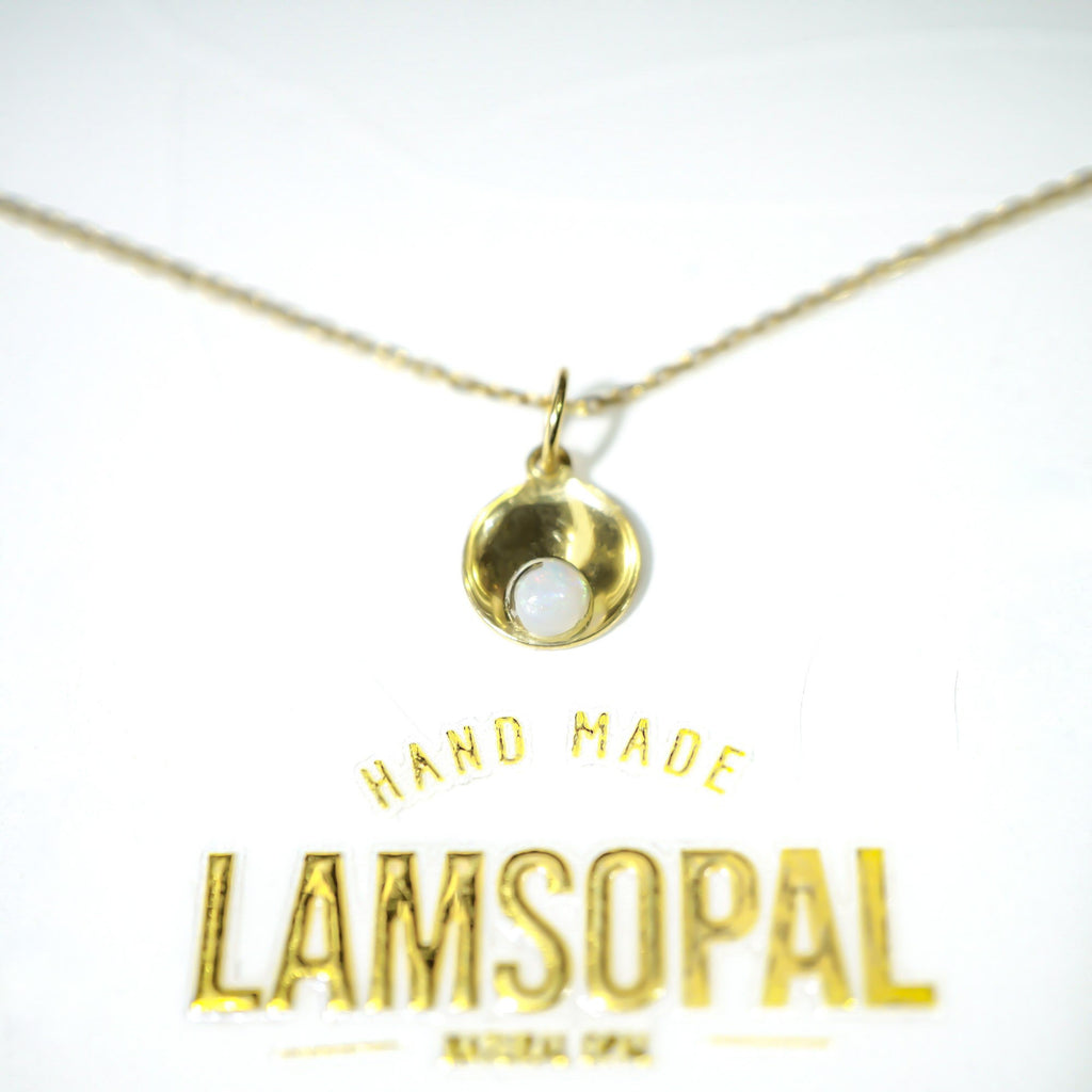 A gold necklace with a small teardrop-shaped pendant featuring a white inlay, displayed on a white background with the brand name 'LAMSOPAL' printed below.