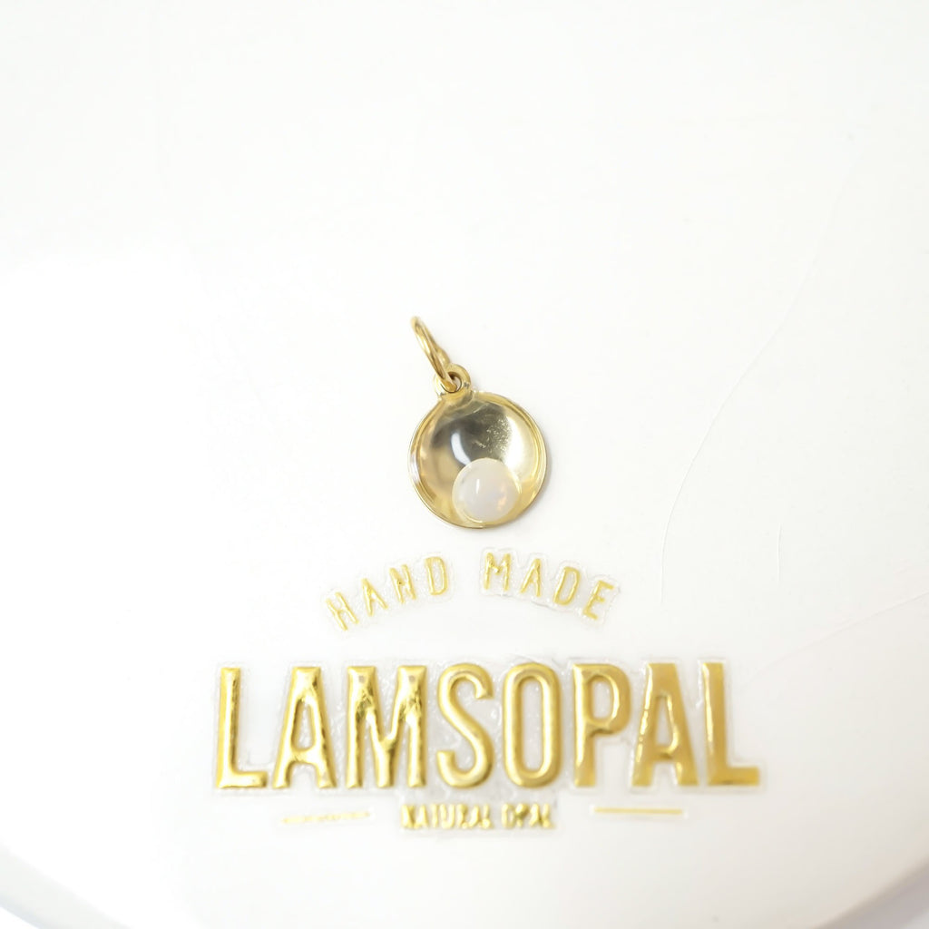 A small gold pendant charm with a white pearl-like center, displayed above gold text reading 'HAND MADE LAMSOPAL' on a white background.