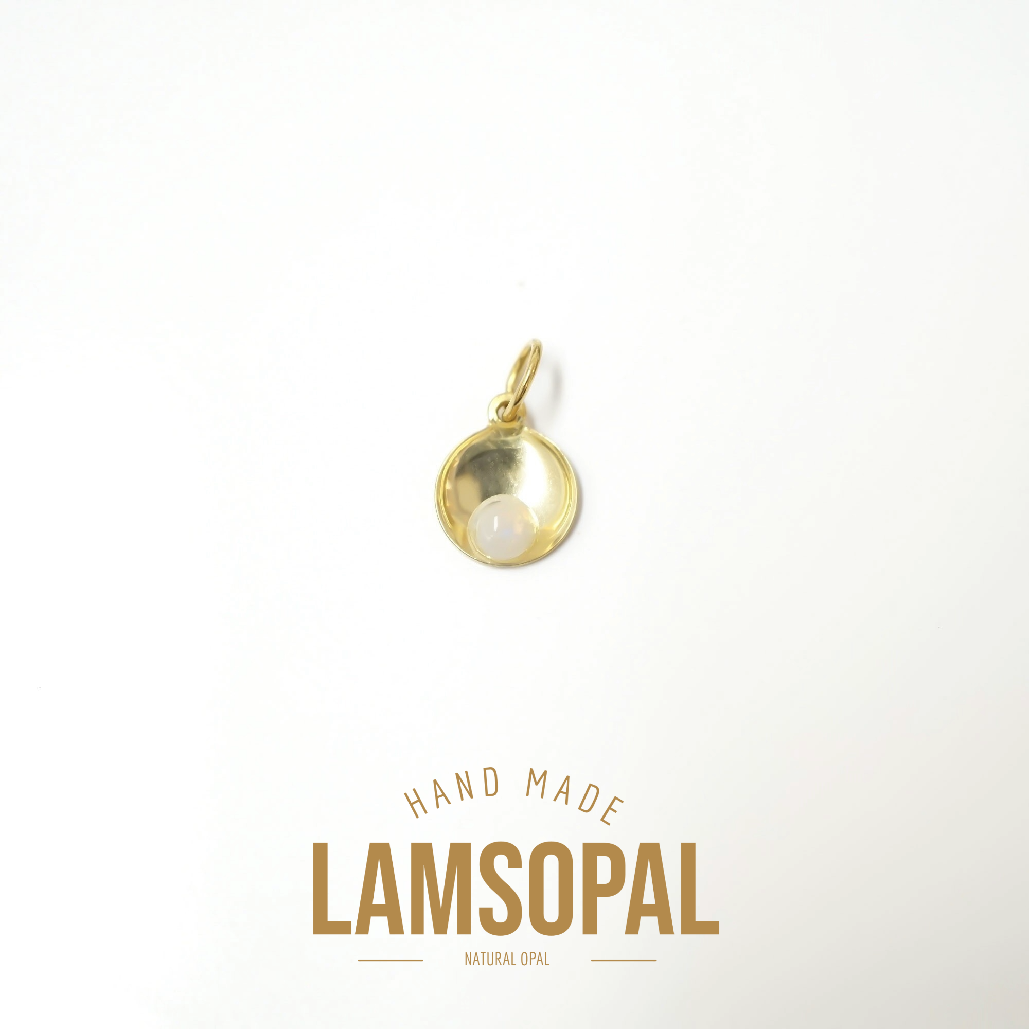 A small gold pendant charm with a natural white opal in a half-circle setting, displayed on a clean white background with 'HAND MADE LAMSOPAL NATURAL OPAL' text below.