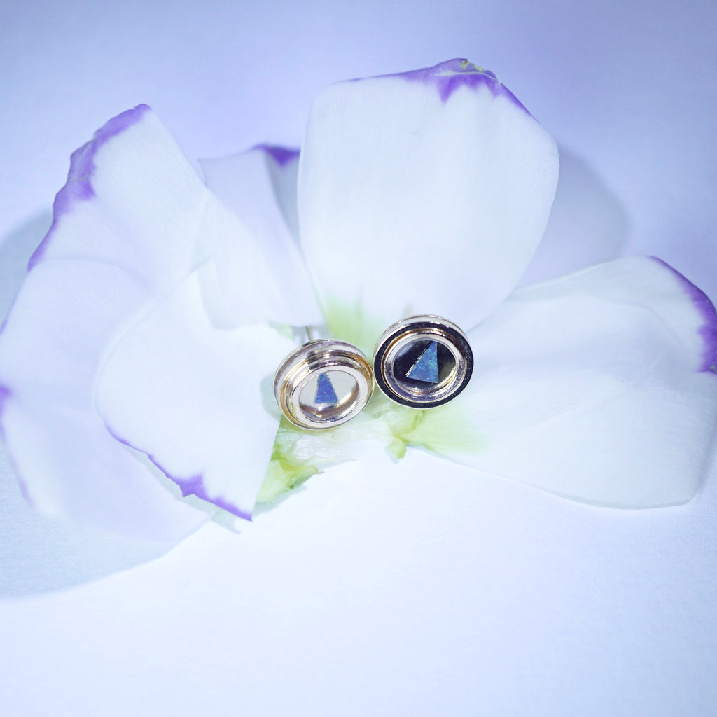 Pair of opal earrings on a white flower with a purple background