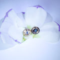 Pair of opal earrings on a white flower with a purple background