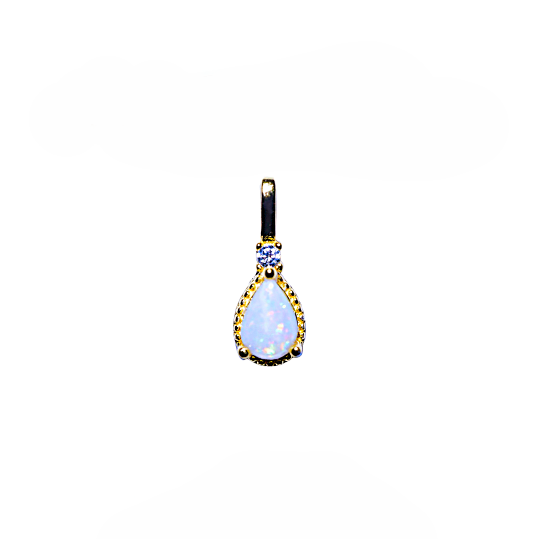A teardrop-shaped pendant featuring a white opal gemstone in a gold bezel setting, accented with a small round blue gemstone and black enamel details at the top, shown against a plain white background.