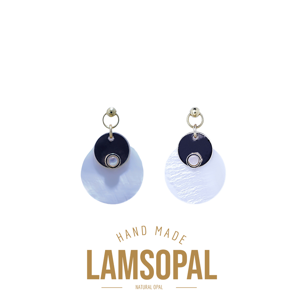 A pair of handmade Lamsopal natural opal dangle earrings on a white background, featuring a dark navy blue circular top with a small silver bezel and a larger light blue-white textured circular drop below. The brand name 'LAMSOPAL' is printed in gold at the bottom.