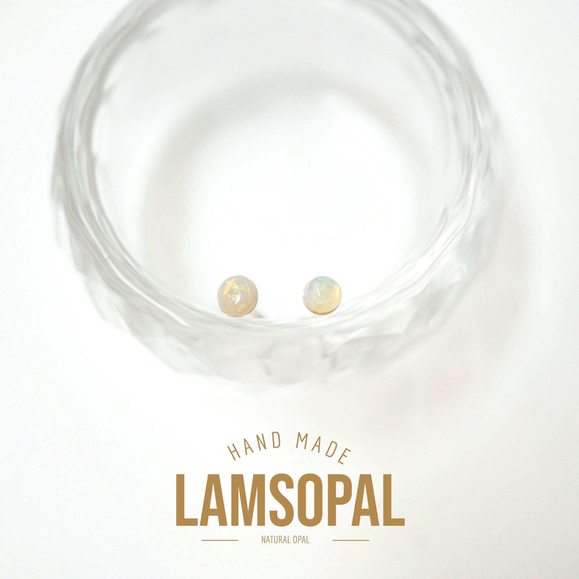 Two small iridescent natural opal stud earrings displayed inside a clear textured glass bowl on a white background, with the text 'HAND MADE LAMSOPAL NATURAL OPAL' below.
