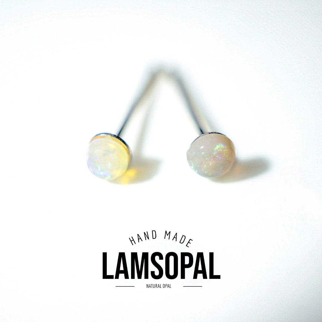 A pair of natural opal stud earrings with round iridescent cabochons on silver posts, shown on a white background with a 'LAMSOPAL' brand logo overlay.