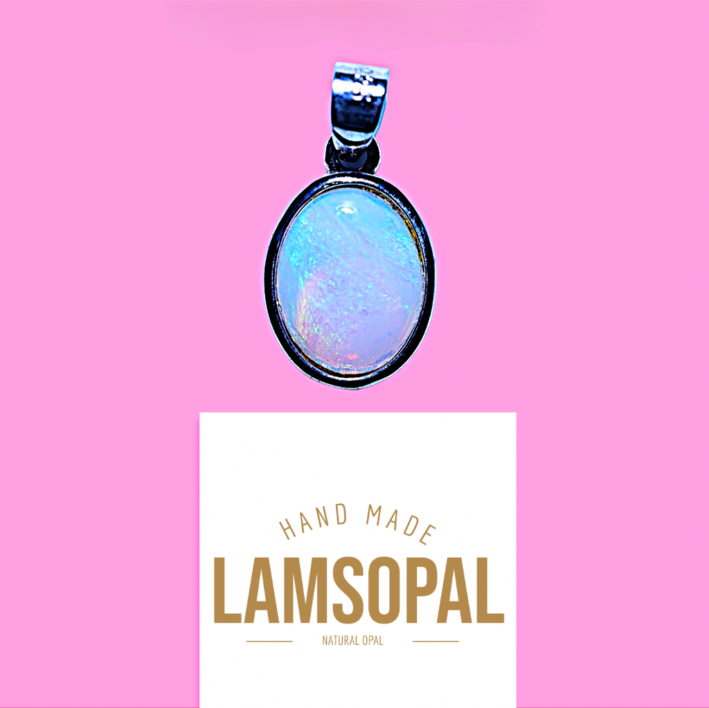 An oval pendant with a black bezel and a light blue iridescent opal center, shown above a white card that reads 'HAND MADE LAMSOPAL NATURAL OPAL' on a solid pink background.