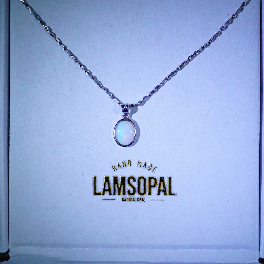 A silver chain necklace with a round iridescent white pendant displayed on a light blue backing card. The card features the brand name 'LAMSOPAL' printed in gold.