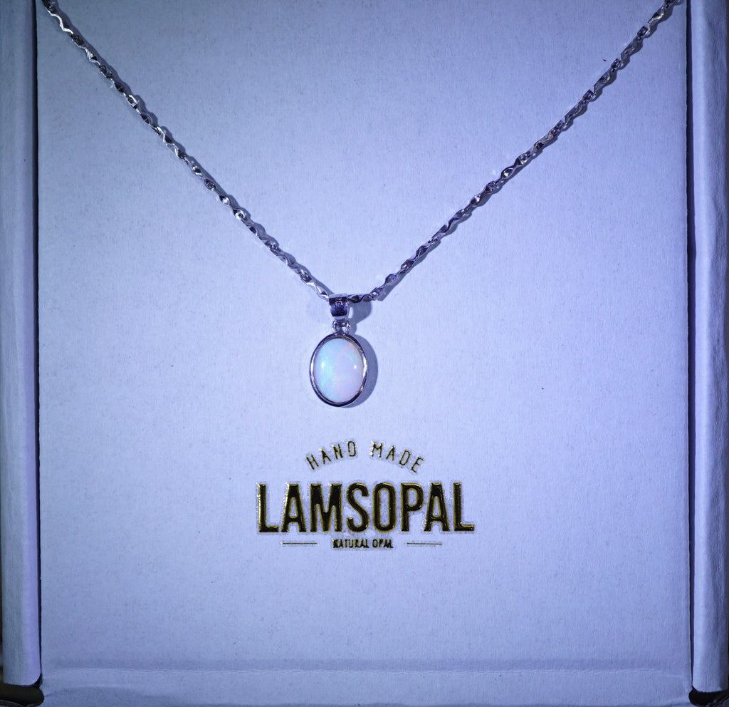 A silver chain necklace with a circular white opal pendant displayed inside a branded Lamsopal gift box.