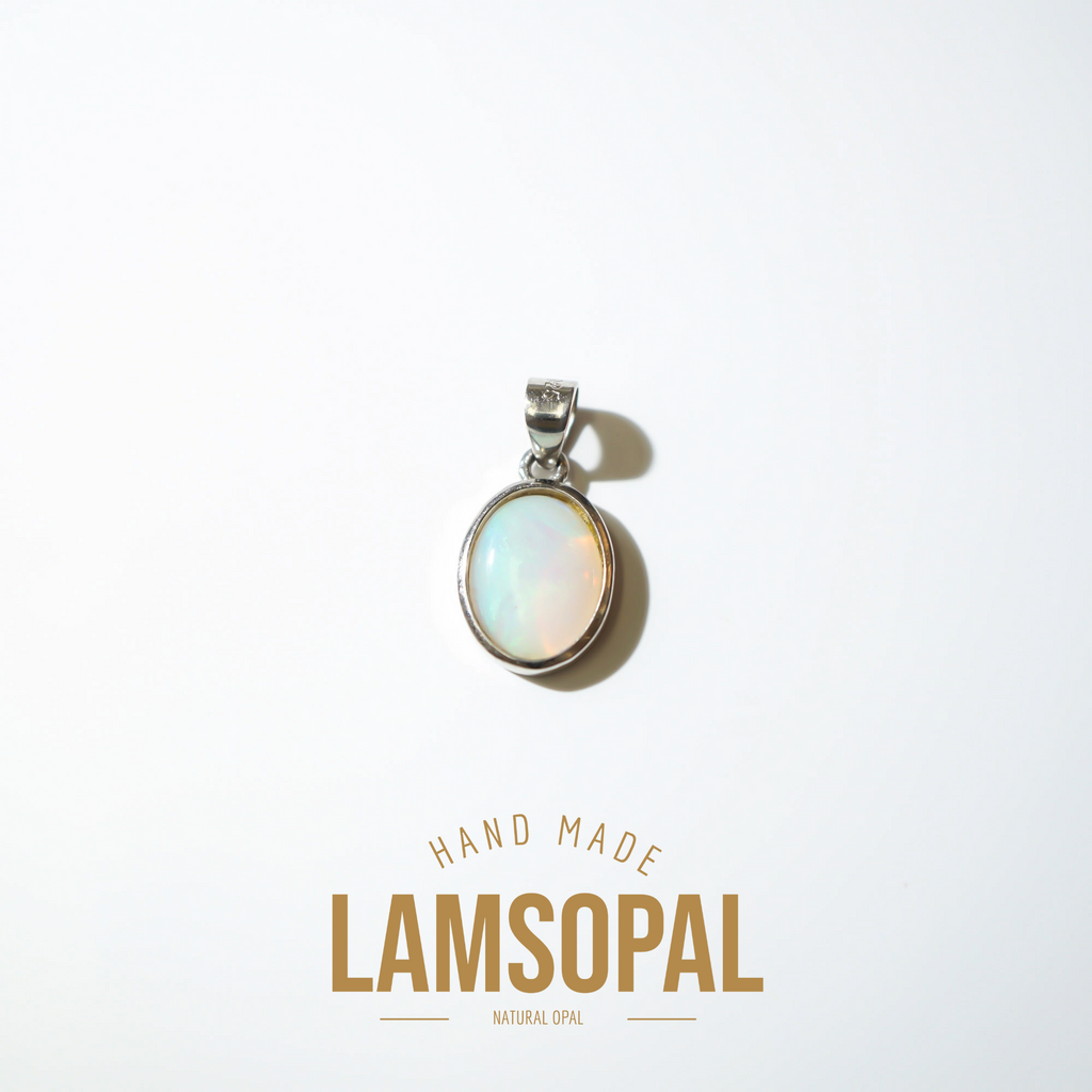 A silver pendant with a round iridescent natural opal cabochon, displayed on a clean white background with a soft shadow. Below the pendant, the text 'HAND MADE LAMSOPAL NATURAL OPAL' is written in gold-colored lettering.