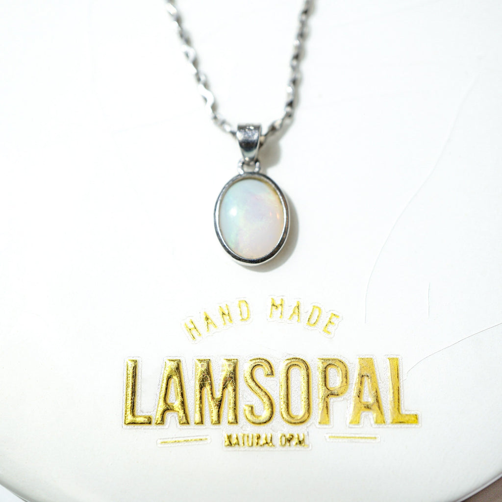 A silver chain necklace with an oval-shaped white opal pendant, displayed on a white background with gold foil text reading 'HAND MADE LAMSOPAL NATURAL OPAL'.