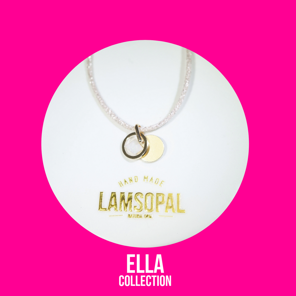 A delicate necklace with a clear beaded chain and a double charm consisting of a gold ring and a flat gold disc, presented on a white circular card with the brand name 'Lamsopal' and collection 'Ella Collection' on a vibrant pink background.