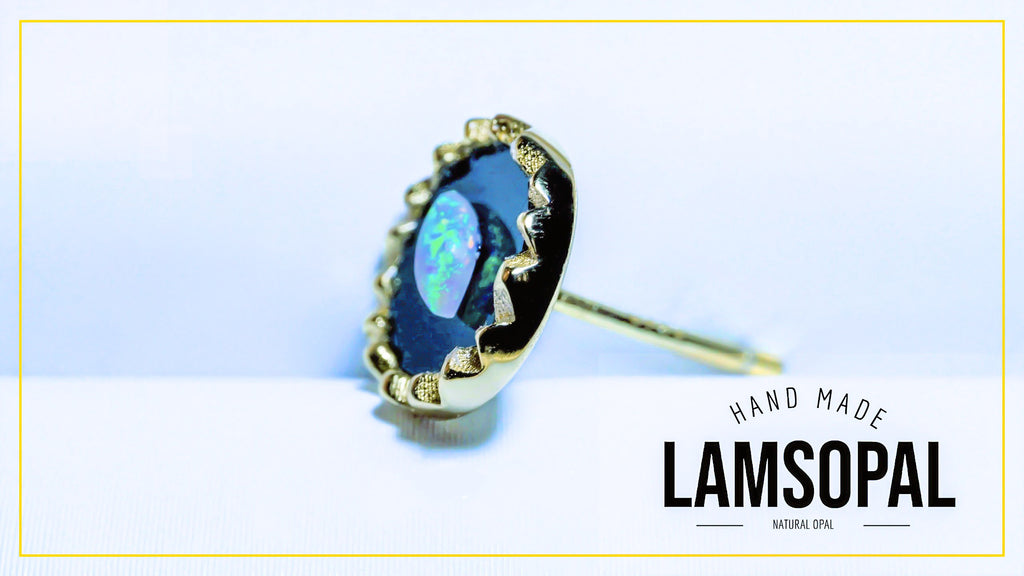 A single Lamsopal hand-made natural opal ring with a gold bezel setting, displayed on a light blue and white background with a gold border and brand text overlay.