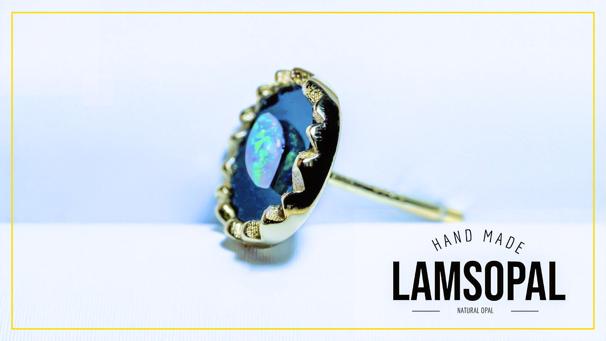 A single Lamsopal hand-made natural opal ring with a gold bezel setting, displayed on a light blue and white background with a gold border and brand text overlay.
