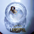 A handmade Lamsopal natural opal heart charm with a gold clasp, displayed inside a clear glass bowl on a white surface with a branded gold logo at the bottom.