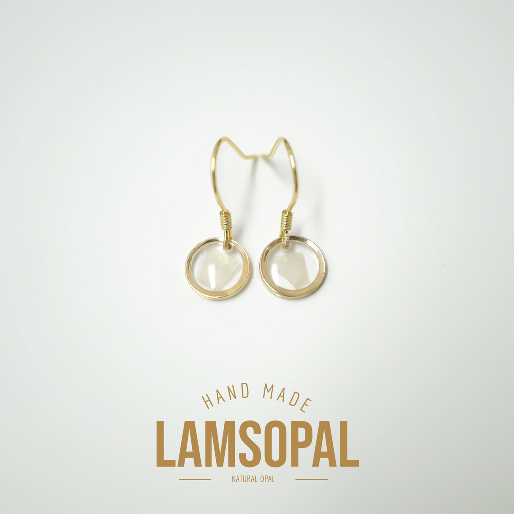 A pair of gold-tone drop earrings with circular natural opal charms, displayed on a clean white background with a gold 'LAMSOPAL' brand logo and 'HAND MADE' text below.