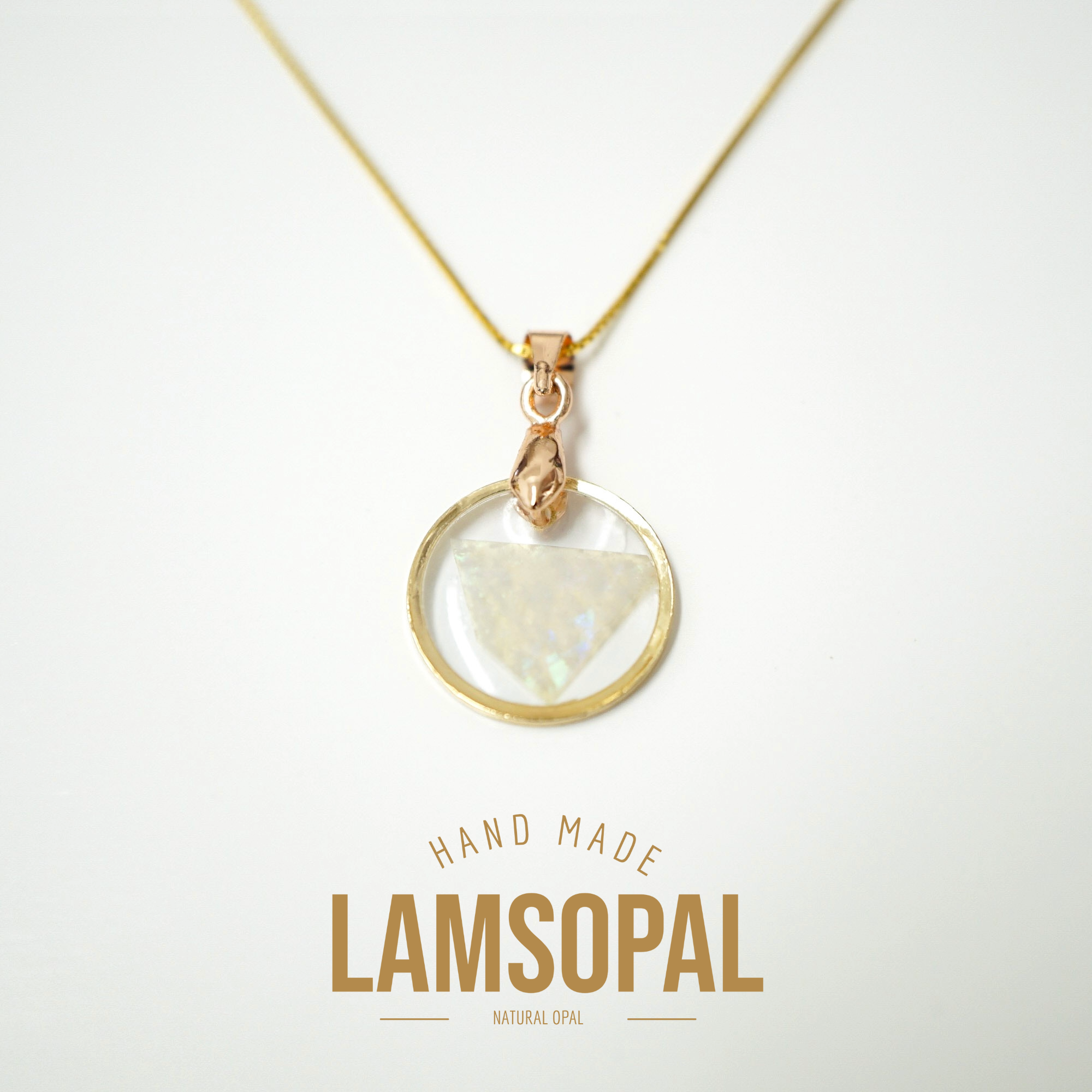 A gold necklace with a circular pendant containing a natural iridescent opal, displayed on a clean white background with 'LAMSOPAL' branding and 'HAND MADE' text below.