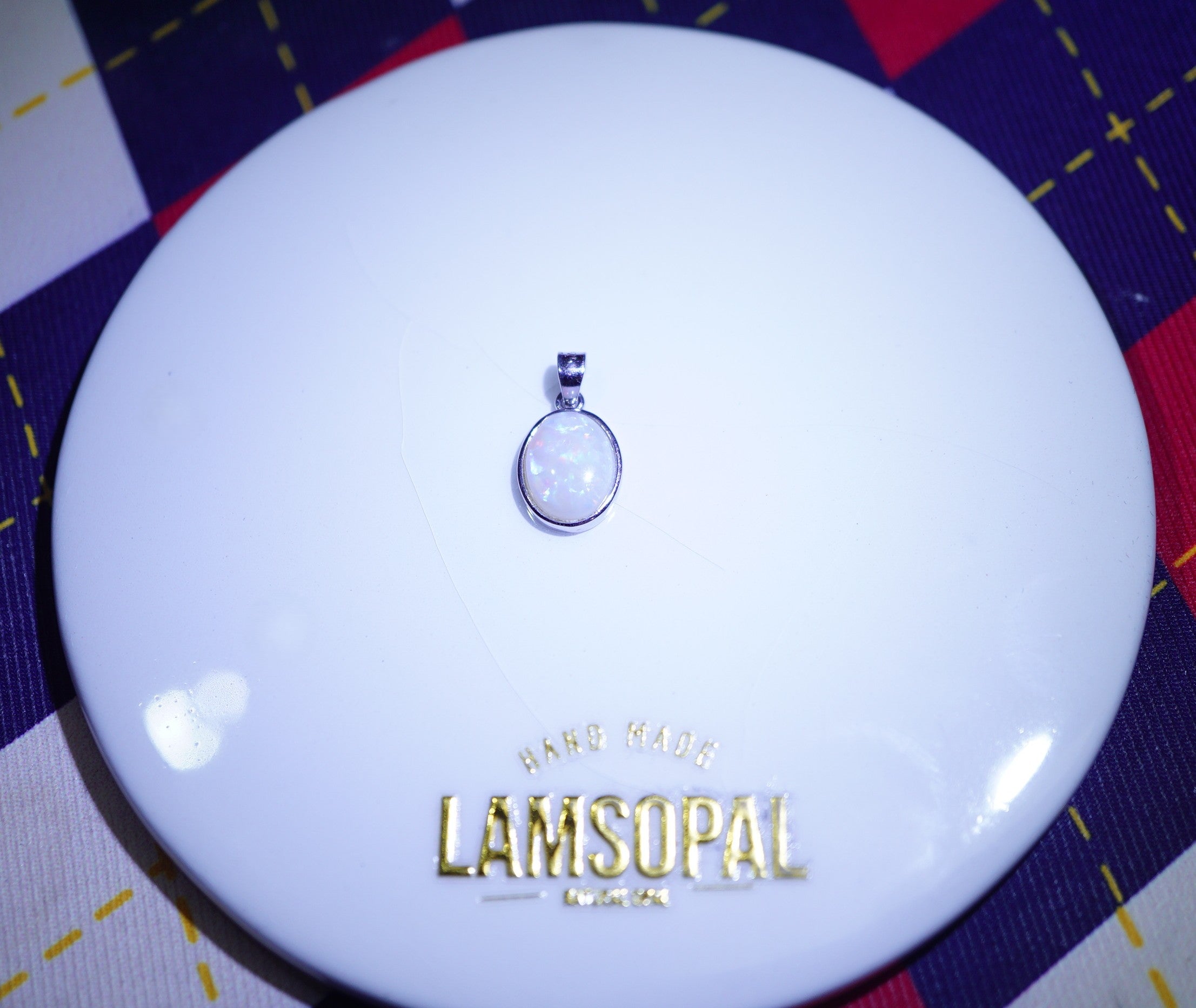 LAMSOPAL pendant on a white dish with a checkered background